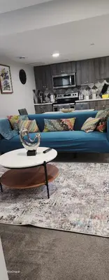a living room with a blue couch and a table at The Vaulted Oasis 2-bedroom with a Garden in Airdrie