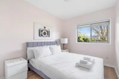 a white bedroom with a bed and a window at Spacious Home with Indoor Pool in Vancouver