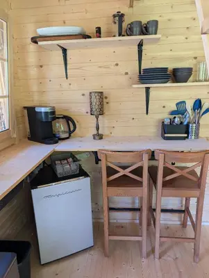 a kitchen with a wooden counter with two chairs and a table at Creekside Bunkies in Roberts Creek