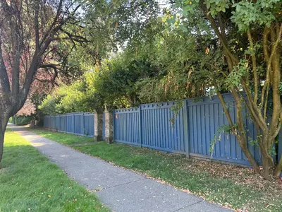 a blue fence with trees next to a sidewalk at Spacious Villa 6BR 3 BA - Free Parking - Near Kitsilano Beach & Attractions - 15' to DT in Vancouver