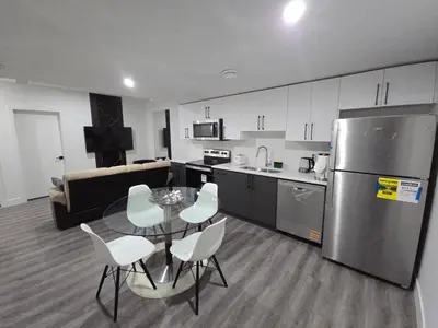 a kitchen with a table and chairs and a refrigerator at 2 bedroom cozy suite in NW edmonton with separate entrance, FreeWifi, driveway Parking, Netflix, AC, airport pickup in Edmonton