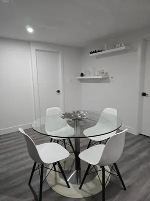 a dining room with a glass table and white chairs at 2 bedroom cozy suite in NW edmonton with separate entrance, FreeWifi, driveway Parking, Netflix, AC, airport pickup in Edmonton