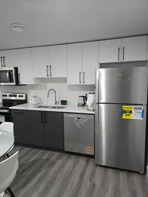 a kitchen with a stainless steel refrigerator and white cabinets at 2 bedroom cozy suite in NW edmonton with separate entrance, FreeWifi, driveway Parking, Netflix, AC, airport pickup in Edmonton