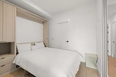 a white bedroom with a bed and a window at Brand new suite downtown Kelowna - walk everywhere! in Kelowna