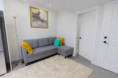 a living room with a gray couch and a rug at Cozy Quarters Your Comfy Haven in Calgary