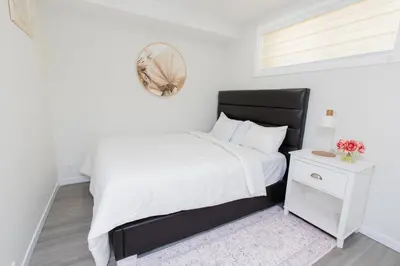 a white bedroom with a white bed and a mirror at Cozy Quarters Your Comfy Haven in Calgary
