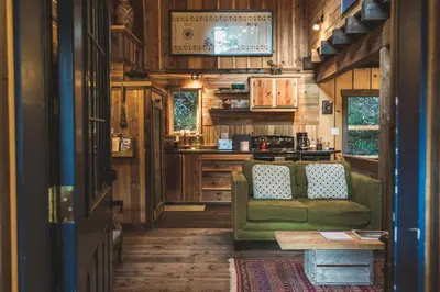 a living room with a green couch and a kitchen at Logden Lodge in Nelson