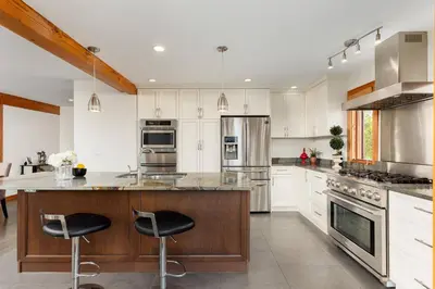 a kitchen with white cabinets and stainless steel appliances at Quiet Modern Dundadrave Oasis in West Vancouver