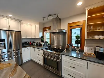 a kitchen with white cabinets and stainless steel appliances at Quiet Modern Dundadrave Oasis in West Vancouver