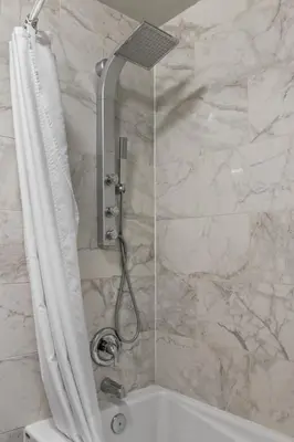 a shower in a bathroom with a marble wall at Chic Mountain View - Pool & HotTub - Fireplace - BBQ! in Canmore