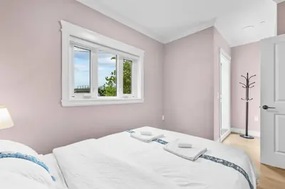 a white bedroom with a bed and a window at Modern Private 3BR House in Vancouver