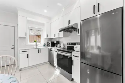 a kitchen with white cabinets and a stainless steel refrigerator at Modern Private 3BR House in Vancouver