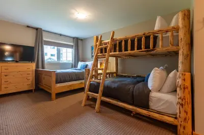 a bedroom with two bunk beds and a tv at Timberline - Spruce Lodge by Fernie Central Reservations in Fernie