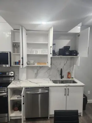 a kitchen with white cabinets and a stainless steel sink at Home in Northwest Calgary in Calgary