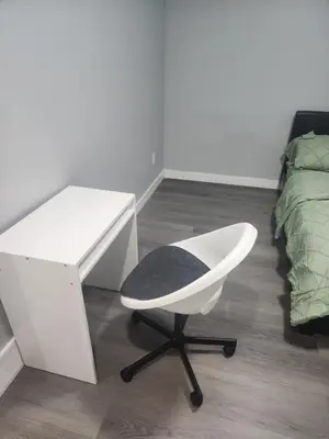 a white desk and a chair in a bedroom at Home in Northwest Calgary in Calgary