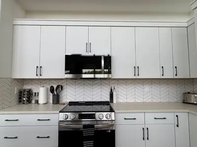 a kitchen with white cabinets and a stove top oven at The Lamp House in Nordegg