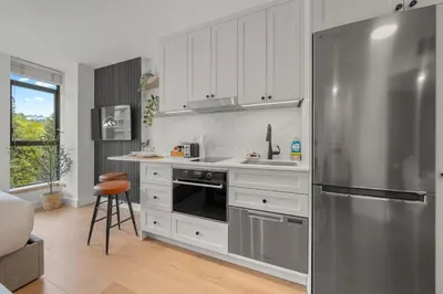 a kitchen with white cabinets and a stainless steel refrigerator at The Summit Room Whistler Village in Whistler