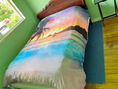 a colorful comforter on a bed in a room at surrey central green bamboo house in Surrey