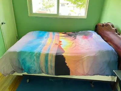 a bed with a colorful comforter on it at surrey central green bamboo house in Surrey