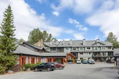 a large building with cars parked in a parking lot at Whistler Corner Loft Next to lift with Amazing views! in Whistler