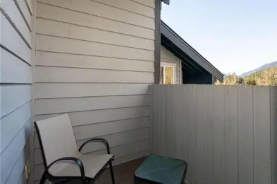a chair sitting on a porch next to a fence at Whistler Corner Loft Next to lift with Amazing views! in Whistler