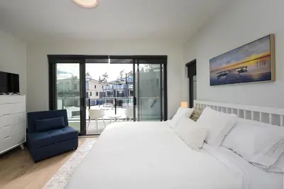 a bedroom with a large white bed and a blue chair at Luxury Saratoga Beach Town Home in Oyster Bay