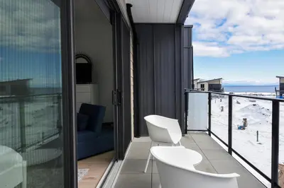 a balcony with two white chairs and a view of the beach at Luxury Saratoga Beach Town Home in Oyster Bay
