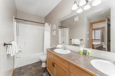 a bathroom with a sink and a toilet and a mirror at Evergreen Escape - 2 Bedroom Condo with Pool & Hot Tub in Canmore