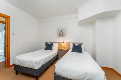two beds in a room with white walls at Evergreen Escape - 2 Bedroom Condo with Pool & Hot Tub in Canmore