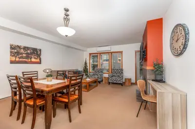 a dining room with a table and chairs and a clock at Evergreen Escape - 2 Bedroom Condo with Pool & Hot Tub in Canmore
