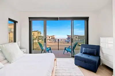 a bedroom with a bed and a chair and a balcony at Family-Friendly Beachside Bliss in Oyster Bay