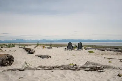 a beach with two beach chairs and driftwood in the sand at Family-Friendly Beachside Bliss in Oyster Bay