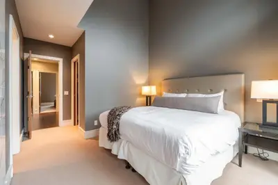 a bedroom with a large white bed and a hallway at Fitzsimmons Walk 37 by Outpost Whistler in Whistler