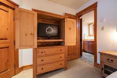 a living room with a tv and a dresser with a dresser at Foxglove 16 by Outpost Whistler in Whistler