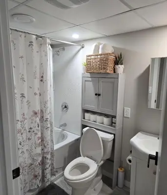 a bathroom with a toilet and a shower curtain at Cozy 2 bedroom basement with side entrance in Bélanger