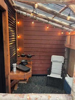 a patio with a table and a chair and lights at Rustic Guesthouse in Sayward