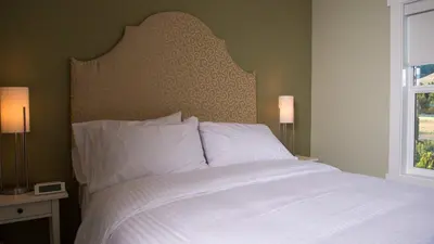 a bedroom with a bed with white sheets and a window at Klippers Guest Suites in Cawston