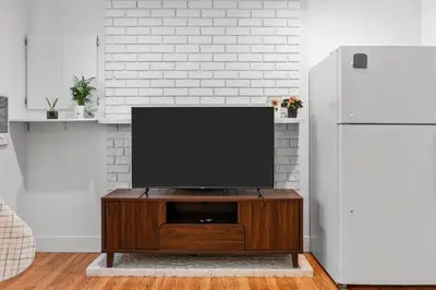 a flat screen tv sitting on top of a wooden entertainment center at Cozy 2BR Suite Near White Rock Beach in Surrey