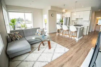 a living room with a couch and a table and a kitchen at Ventura in Downtown in Abbotsford