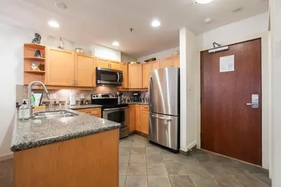 a kitchen with wooden cabinets and a stainless steel refrigerator at Glacier Lodge 216 by Outpost Whistler in Whistler
