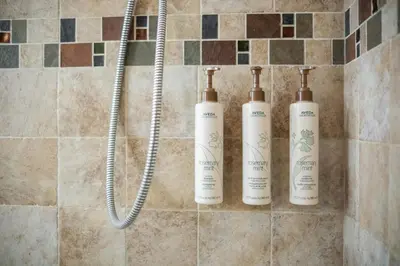 three shampoo bottles are lined up in a shower at Glacier Lodge 216 by Outpost Whistler in Whistler