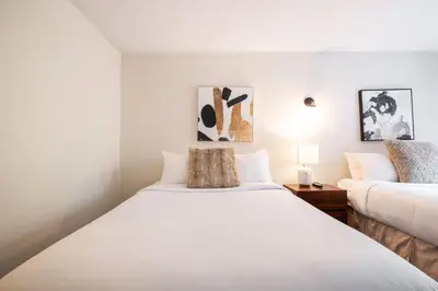 a white bedroom with two beds and a lamp at Glacier Lodge 216 by Outpost Whistler in Whistler