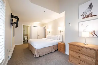 a bedroom with a large white bed and a dresser at Glacier Lodge 309 by Outpost Whistler in Whistler