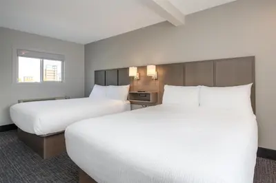 two beds in a hotel room with white sheets at Coast Penticton Hotel in Penticton
