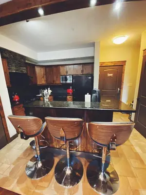 a kitchen with a bar with three bar stools at Sable Ridge Retreat in Radium Hot Springs