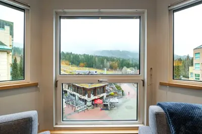 a room with three windows with a view of a building at Le Chamois 508 by Outpost Whistler in Whistler
