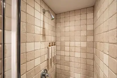 a bathroom with a shower with tan tiles at Le Chamois 508 by Outpost Whistler in Whistler