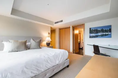a bedroom with a white bed and a desk at Le Chamois 508 by Outpost Whistler in Whistler
