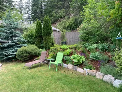 two chairs and a table in a garden at West facing Waterfront Retreat with private beach, dock access & private buoy in Blind Bay