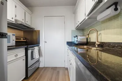 a kitchen with white cabinets and a sink at Suite near Downtown, BMO, Stampede, Free Parking in Calgary